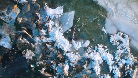 Aerial-top-down-view-of-ice-lake-in-south-coast-of-Iceland,-huge-expanse-of-an-empty-and-barren-frozen-lake-full-of-ice-cracks-and-melting-down