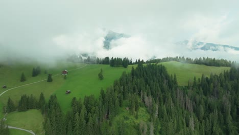 Eine-Drohne-Fliegt-über-Einem-üppigen-Grünen-Hügel,-Der-Von-Wolken-Bedeckt-Ist