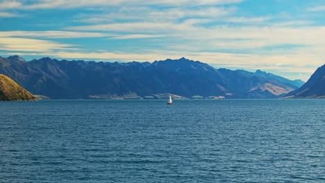 Panoramic-orbit-around-sailboat-in-middle-of-Lake-Hawea-against-stunning-mountains