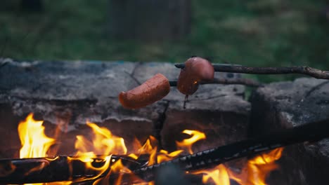 Braten-Von-Würstchen-Am-Spieß-Auf-Einem-Lagerfeuer-Nach-Einbruch-Der-Dunkelheit