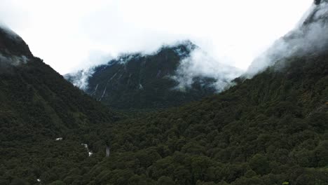 Aerial-pan-across-moody-dark-tropical-forested-jungle-in-Milford-Sound-covered-with-clouds