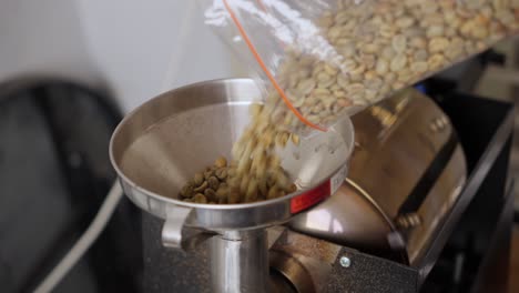 Unroasted-coffee-beans-being-poured-into-a-coffee-roaster