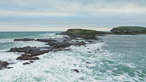 Aerial-panoramic-dolly-abvoe-rocky-rough-whitewash-churning-in-waters-alongside-cliff