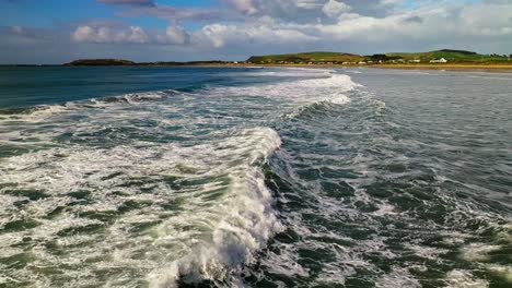 Sideview-tracking-pan-follows-ocean-waves-and-whitewash-crashing-on-water-surface