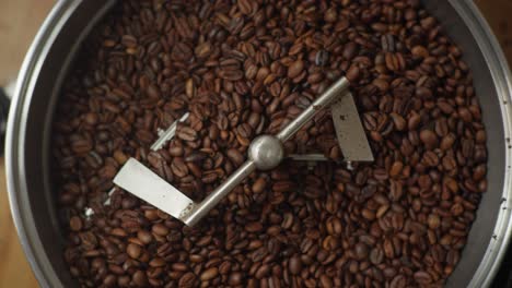 Top-Down-view-above-black-Coffee-grains-rolling-into-a-grinder-Closeup-process-in-the-making