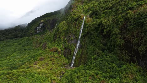 Aerial-parallax-around-steep-tropical-waterfall-cascading-down-into-forest