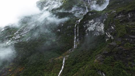 Aerial-panoramic-parallax-upward-angle-of-waterfall-cascading-between-clouds