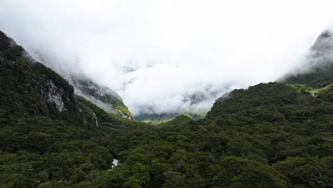 Aerial-establishing-pan-above-dense-tropical-forest-covered-with-clouds-in-distance