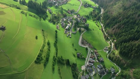 Overhead-aerial-tilt-down-view-captures-cars-navigating-a-winding-road-in-the-quaint-village-of-La-Val,-South-Tyrol,-Italy