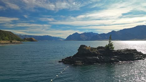 Aerial-dolly-along-buoy-line-out-to-island-revealing-beautiful-Lake-Hawea-in-New-Zealand