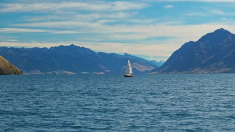 Panorámica-Aérea-De-Camiones-Alrededor-De-Un-Velero-Rojo-En-El-Lago-Hawea-En-El-Día-De-Verano.