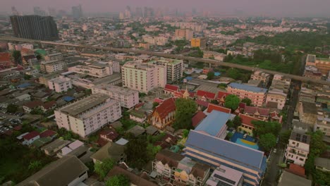 Urban-sunset-over-Bangkok-with-cityscape-and-high-rises---aerial-sweeping-view
