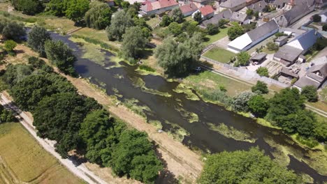 Stagnant-canal-running-through-small-village-of-Batya,-Hungary,-aerial-view