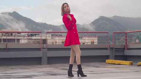 Amidst-the-urban-sprawl,-a-young-girl-of-Hispanic-heritage-stands-elegantly-in-her-short-red-dress-atop-a-rooftop