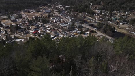 drone-fly-above-pine-tree-forest-and-revealing-town-of-Saint-Côme-in-Quebec