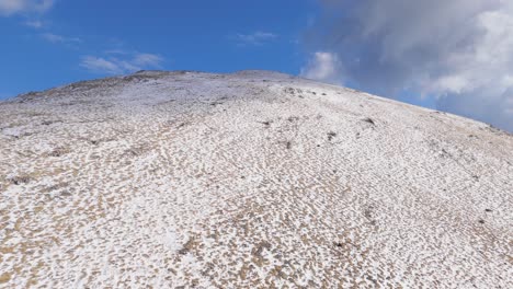 Fast-aerial-ascend-along-speckled-snow-and-rocky-mountain-terrain-of-Peloponnese-region