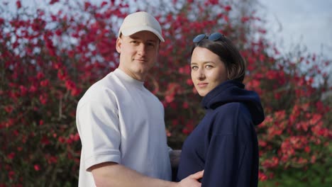 Beautiful-caucasian-couple-together-near-blossoming-Chinese-quince-shrub