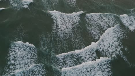 Aerial-view-of-a-breaking-wave-on-a-beach,-captured-during-a-mesmerizing-sunset