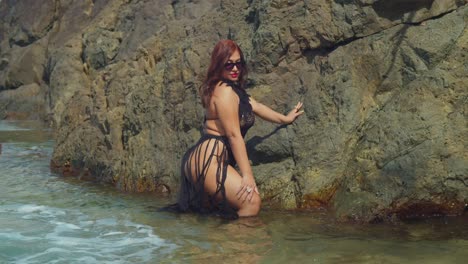 Amidst-the-splendor-of-Tobago's-beaches,-a-woman-in-a-bikini-enjoys-the-solitude-of-a-rock-pool-nestled-along-the-shore