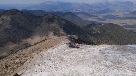 Absteigende-Luftaufnahme-Folgt-Einem-Steilen,-Schneebedeckten-Bergpfad-In-Den-Bergen-Des-Peloponnes-In-Griechenland