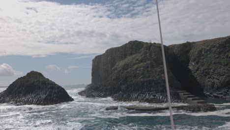 Hand-held-shot-of-the-landing-site-at-the-Isle-of-Staffa-with-large-waves-crashing