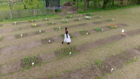 Young-woman-walking-through-expansive-flower-garden-of-colour,-aerial
