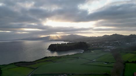 The-rising-sun-casts-its-golden-glow-over-the-hills-and-ocean-coastline-of-the-Portuguese-Riviera-in-Açores,-Portugal,-epitomizing-the-beauty-and-tranquility-of-coastal-landscapes