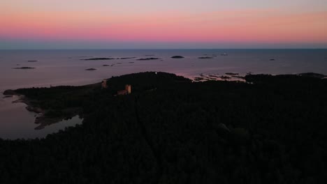Aerial-view-backwards-over-the-Jussaro-island,-vibrant,-summer-dusk-in-Finland