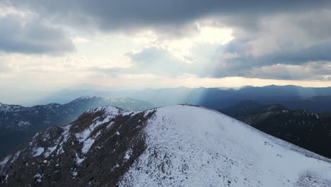 Sun-ray-breaking-between-clouds-casting-on-Peloponnese-mountain-valleys-with-snow