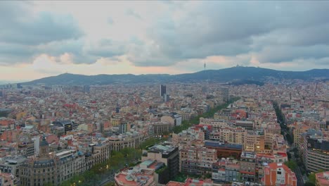Barcelona-cityscape-with-dense-buildings-under-cloudy-skies,-daylight,-aerial-view