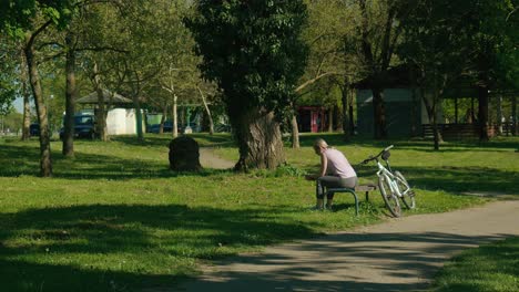 Quiet-moment-by-Jarun-Lake-in-Zagreb,-with-a-person-resting-by-a-bike