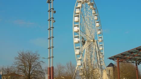 Low-angle-shot-of-Ferris-wheel-moving-in-the-old-historic-harbor-town-of-La-Rochelle,-France-on-a-sunny-day