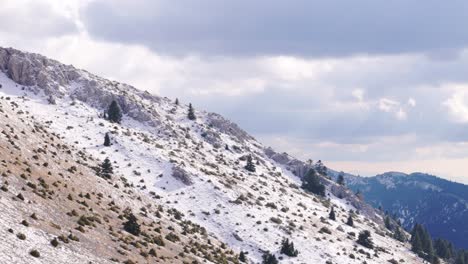 Panorámica-Aérea-De-Camiones-A-Lo-Largo-De-La-Empinada-Ladera-Rocosa-De-Las-Montañas-Del-Peloponeso-Revela-El-Valle-Detrás