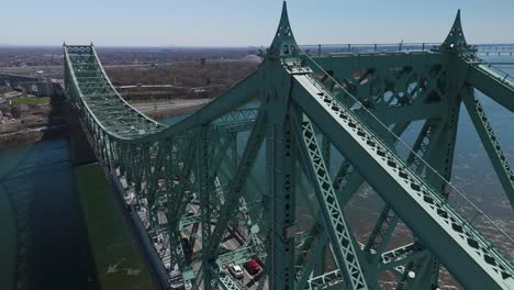 The-Jacques-Cartier-Bridge-Montreal-Island,-Montreal,-Quebec,-Canada-aerial-footage-with-car-crossing-Saint-Lawrence-River-leaving-behind-the-cityscape-of-the-city