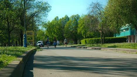 Sunny-day-at-Jarun-Lake,-Zagreb,-with-pedestrians-enjoying-a-tree-lined-pathway