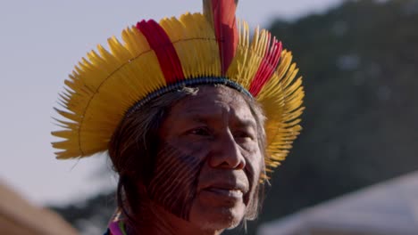 An-indigenous-tribal-man-wearing-a-colorful-headdress-looks-straight-into-the-camera