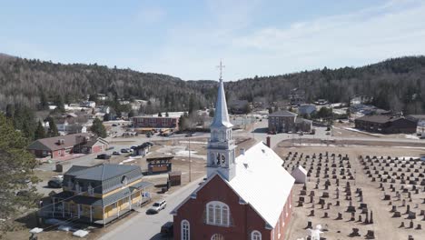 drone-above-Saint-CômeLanaudière-region-of-Quebec-Canada-fly-above-old-colonial-church-in-mountains-pine-tree-forest-valley