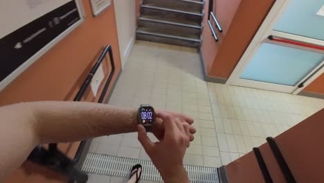 Man-wearing-Apple-Watch-fitness-tracker-walks-through-hallway-towards-swimming-pool