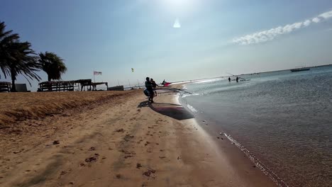 Man-With-Wing-Foil-Board-And-Wings-Walking-Towards-Red-Sea-In-Dahab,-Egypt