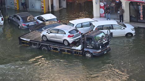 On-April-23,-2024,-car-owners-tow-their-vehicles-for-recovery-on-a-flooded-street-in-the-northern-Emirates-of-the-UAE-following-record-breaking-rains-in-the-country