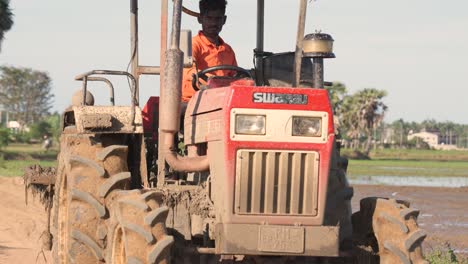 Sri-Lankan-farmer-preps-rice-land-at-sunset-with-red-tractor-while-birds-soar-for-insects