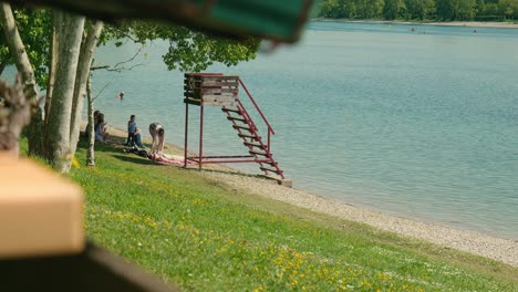 Lakeside-tranquility-at-Jarun-Lake,-with-a-lifeguard-tower-and-people-enjoying-a-sunny-day