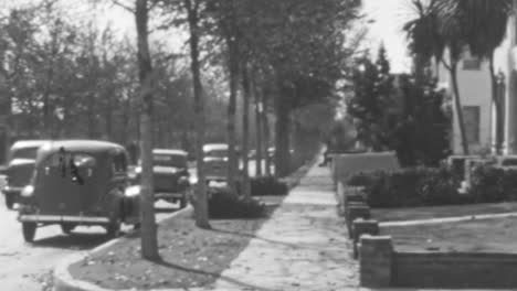 Escena-Callejera-Antigua-De-Los-Años-30-Con-Coches-Aparcados-Y-árboles-En-Una-Tarde-Soleada