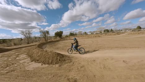 FPV-Aéreo-Siguiendo-A-Un-Piloto-De-Motocross-A-Través-De-Una-Pista-De-Tierra-En-Taylor,-Arizona