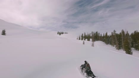 Aerial-FPV-Following-Snowmobile-Rider-Speeding-Across-Snow-Covered-Sharkstooth-Peak-Landscape-In-Colorado