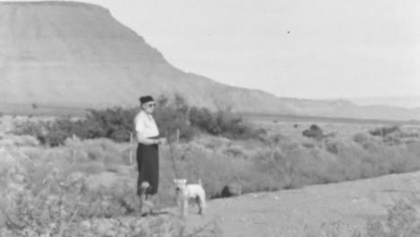 Una-Mujer-Vestida-De-época-Pasea-A-Un-Perro-En-Un-Paisaje-Lejano-Rodeado-De-Montañas