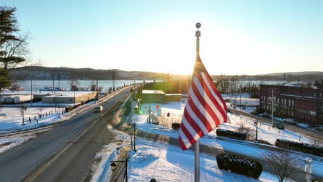 American-flag-waving-in-Columbia,-Pennsylvania-during-snowy-sunset-in-winter