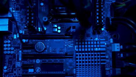 Blue-hued-close-up-of-a-computer-motherboard-highlighting-circuit-details