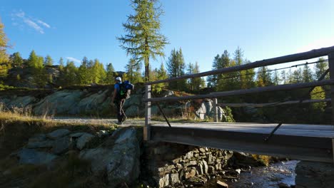 Male-Hiker-Walking-Over-Bridge-In-Valmalenco-Region,-Italy