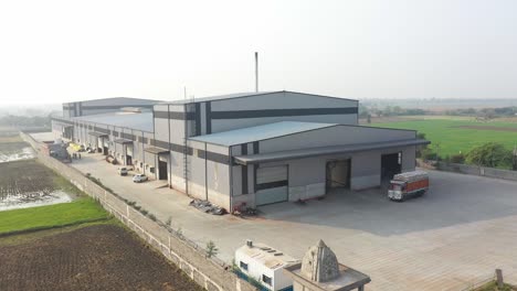 aerial-drone-view-drone-camera-moving-forward-showing-a-truck-loaded-with-food-in-front-of-factory-and-go-down